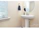 Powder room features a pedestal sink, rounded mirror, and clean, neutral decor at 6961 Liverpool Ct, Fort Mill, SC 29707