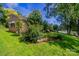 Side view of a brick home with green grass and mature trees, showcasing the property's natural surroundings at 823 Yuma St, Charlotte, NC 28213