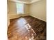 A well lit bedroom featuring a large window and wood-style flooring at 9541 Shannon Green Dr, Charlotte, NC 28213
