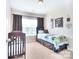 Neutral bedroom with a crib and bed next to the window at 9792 Ravenscroft Nw Ln, Concord, NC 28027
