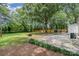 Backyard patio area with brick pavers, flower bed, trees and a privacy fence at 1006 Home Trl, Gastonia, NC 28052