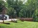 Professionally landscaped backyard with a wooden deck, lush grass, and mature shade trees at 103 Northchase Dr, Concord, NC 28027