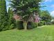 Charming brick home with lush landscaping, mature trees, and an inviting front yard at 103 Northchase Dr, Concord, NC 28027