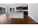 Open-concept kitchen with a large island, dark cabinets, stainless appliances, and wood flooring at 10328 Kempsford Dr, Charlotte, NC 28262