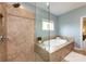 Bright bathroom features a soaking tub and glass enclosed shower with mosaic tile at 14010 Promenade Dr, Huntersville, NC 28078