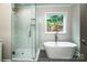Modern bathroom with glass-enclosed shower and separate soaking tub and backyard view at 240 Mark Ryan Ln, Dallas, NC 28034