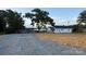 Exterior shot of white home situated on land showing trees and a spacious gravel area at 601 N Johnson St, Monroe, NC 28112