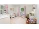Bright bedroom featuring a white crib, striped rug, pink curtains, and a dollhouse near the window at 935 Trentle Ct, Charlotte, NC 28211