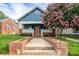 Charming blue home featuring a welcoming porch, brick accents, an orange front door, and a beautiful flowering tree at 1008 Vanizer St, Charlotte, NC 28208