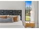 A bright main bedroom with an artistic headboard, wooden nightstand, and outdoor views at 113 Prince St, Belmont, NC 28012