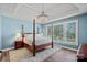 Spacious bedroom with a four-poster bed, tray ceiling, chandelier, and windows overlooking the backyard at 116 Ivy Hollow Ln, Mooresville, NC 28117