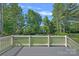 View of fenced backyard from a large deck with gray floors surrounded by lush green trees at 116 Ivy Hollow Ln, Mooresville, NC 28117