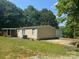 View of the home featuring a covered porch, a concrete patio, and a well-manicured lawn surrounded by mature trees at 121 C & K Dr # 60, Taylorsville, NC 28681