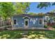 Exterior view of the blue house with light trim, brick pathway, lush lawn and mature trees providing shade at 1500 Pecan Ave, Charlotte, NC 28205