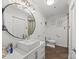 Stylish bathroom with a modern vanity, a round mirror with decorative light fixture, and wainscoting at 17931 Kings Point Dr # E, Cornelius, NC 28031