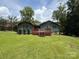 Home's backyard features a red deck and steps, surrounded by a lush green lawn and towering trees at 200 Breslin St, Wadesboro, NC 28170