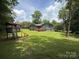 Backyard features play set, a deck on the back of the house, lawn and perimeter trees at 200 Breslin St, Wadesboro, NC 28170