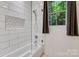 Bright bathroom with a glass-enclosed tub and shower combination, white subway tile, and window view at 2122 Goose Creek Farm Ln, Indian Trail, NC 28079
