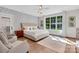 Bright bedroom featuring a tufted headboard, elegant decor, and a sun-filled window with wooded views at 2122 Goose Creek Farm Ln, Indian Trail, NC 28079