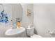A bright half bathroom featuring a pedestal sink, decorative mirror, and toilet with a neutral color scheme at 214 Hidden Lakes Rd, Statesville, NC 28677