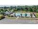 Aerial view of a community pool area with lounge chairs, umbrellas, a pool house, and parking lot in the foreground at 214 Hidden Lakes Rd, Statesville, NC 28677
