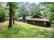 Expansive rear exterior featuring a stone patio with a hammock, lush green lawn, and mature trees offering shade at 3041 Shallowood Ln, Charlotte, NC 28277