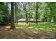 Rear exterior showcasing a spacious yard with mature trees and a patio with lounge furniture and a hammock at 3041 Shallowood Ln, Charlotte, NC 28277