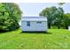 A small white shed with a silver roof sits on a lush green lawn, providing practical storage at 701 Mcswain Rd, Shelby, NC 28150