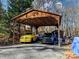 Open carport featuring two pickup trucks, one yellow and one black, with wooden beams and a natural setting at 720 Potneck Rd, Salisbury, NC 28147