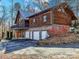 Rustic wooden house with stone foundation and a metal roof, complemented by a three-car garage and a lovely yard at 720 Potneck Rd, Salisbury, NC 28147