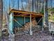 Wood storage shed for firewood with a covering and wooden supports at 720 Potneck Rd, Salisbury, NC 28147
