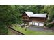 A charming log home with stone accents, a metal roof, and a spacious three-car garage nestled amongst mature trees at 720 Potneck Rd, Salisbury, NC 28147
