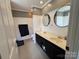 Well-lit bathroom with double vanity, black cabinets, round mirrors, and neutral walls and flooring at 8122 Hutchison Ln, Vale, NC 28168