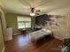 Well-lit bedroom with wood floors and ceiling fan and black and white mural above the bed at 8122 Hutchison Ln, Vale, NC 28168