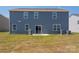 Exterior view of a blue home with a patio, grill, and grassy backyard space at 9529 Cotswood Pl, Gastonia, NC 28056