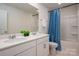 Bright bathroom featuring double sinks, a large mirror, and a shower-tub combo with stylish blue curtain at 9529 Cotswood Pl, Gastonia, NC 28056