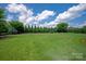 A large, well-maintained backyard with lush green grass, mature trees, and a trampoline at 11008 Strike The Gold Ln, Waxhaw, NC 28173