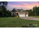 Brick home featuring a three-car garage, well-manicured lawn, and professional landscaping at 11226 Dappled Light Trl, Charlotte, NC 28227