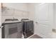 Functional laundry room with modern gray washer and dryer, shelving, and a convenient utility door at 11226 Dappled Light Trl, Charlotte, NC 28227