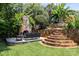 Outdoor living space with stone fireplace, patio, lush landscaping, and terraced stone steps at 117 N Central Ave, Belmont, NC 28012