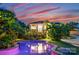 Inviting backyard pool reflecting the home's lights, surrounded by tropical foliage and lounge chairs at 117 N Central Ave, Belmont, NC 28012