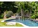 Backyard oasis featuring a unique pool design surrounded by lush tropical landscaping and waterfall at 117 N Central Ave, Belmont, NC 28012