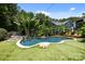 Backyard oasis featuring a unique pool design surrounded by lush tropical landscaping at 117 N Central Ave, Belmont, NC 28012