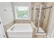 Bright bathroom featuring a soaking tub with window view and a glass-enclosed shower at 1314 San Gabriel Ave, Charlotte, NC 28214