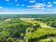 Aerial view showcasing the property and the surrounding wooded area, with distant view of community shopping centers at 13715 Mayes Rd, Huntersville, NC 28078