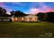 Brick ranch home at dusk with a screened porch and spacious front yard at 13715 Mayes Rd, Huntersville, NC 28078