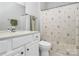 Well-lit bathroom with a white vanity, toilet, and shower with a patterned curtain at 14451 San Paolo Ln, Charlotte, NC 28277