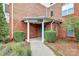 Building entrance featuring manicured shrubs, covered entryway, and brick facade at 14451 San Paolo Ln, Charlotte, NC 28277