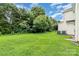 Expansive backyard with lush green lawn, mature trees, and the side of a home featuring AC units at 14911 Taggert Trail Dr, Charlotte, NC 28273