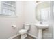 This half-bathroom is a quaint space with a pedestal sink, round mirror, and small window at 14911 Taggert Trail Dr, Charlotte, NC 28273